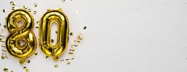 Seksen numaralı altın folyo balonu. 80 yazılı doğum günü ya da yıldönümü kartı. Gri beton arka plan. Yıldönümü kutlaması. Pankart. Boşluğu kopyala