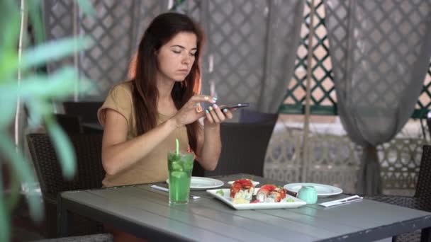 Kaukasierin sitzt in Restaurant und fotografiert ihr Mittagessen mit dem Smartphone. — Stockvideo