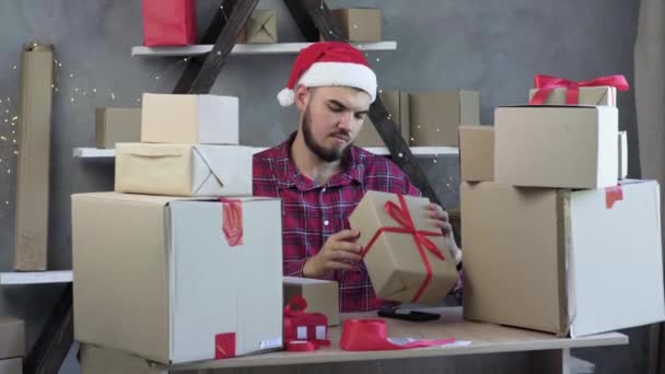 Startup of small business, small and medium business, Lifestyle of a new generation of young entrepreneur, a man in a hat with a claus keeps an inventory of goods using a smartphone. Venda de Natal — Vídeo de Stock