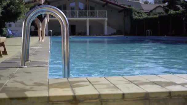 Escada na piscina e pernas femininas caminhando em direção a ele. conceito de férias em um resort de elite. — Vídeo de Stock