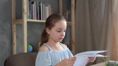 Evde dizüstü bilgisayarla ödev yapan akıllı bir anaokulu öğrencisi. Çocuk çalışmak için aletler kullanıyor..