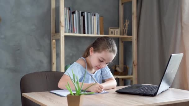 Adolescente colegiala haciendo la tarea con el ordenador portátil en casa. El niño usa aparatos para estudiar. Educación y educación a distancia de los niños. — Vídeos de Stock