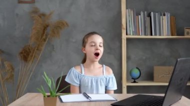 Liseli kız evde ödev yaparken masada otururken esniyor. Yorgun bir bayan öğrenci internetten ders çalışıyor ve uykuya dalıyor. İlkokul öğrencisi. Yorgunluk.