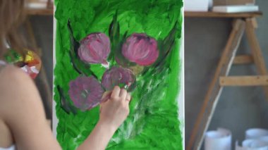 Sanatçının elini tuvalin üzerine boyalar çizerek yeşil arka plan üzerine yakın plan çizer. Sanat atölyesi yaratıcılık konsepti