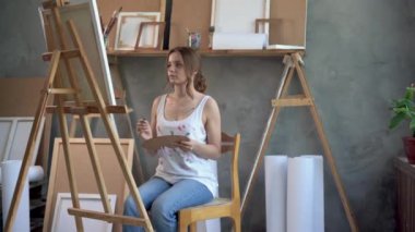 Modern bir yağlı boya resim üzerinde çalışan, fırça darbeleriyle hareket eden yetenekli bir sanatçı. Büyük resim sehpanın üzerinde duruyor. Hobi yaratıcılık için fikirler arıyor. Sanat konsepti