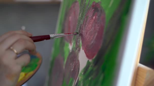 Närbild av konstnärerna kvinnlig hand, hon målar en bild på duk med en pensel och akrylfärger. — Stockvideo