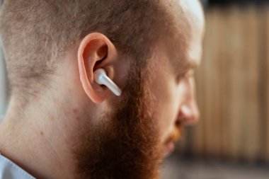 young bearded guy In wireless white headphones, close-up. headphone photo. Sporty lifestyle. Listening music