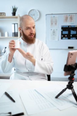 Telehealth concept. male doctor using smartphone and tripod talk to patient recommended pills vitamins make telemedicine online video call. consultation in telemedicine. copy space