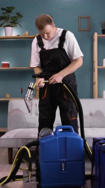 Cleaner using extractor machine to clean sofa at house. Removing dirt from sofa with extractor. vertical video