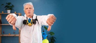 sad dissatisfied Elderly pest control worker showing thumbs down dislike gesture inside infested house. Exterminator in protective suit holding spray bottle with insecticide for home. banner