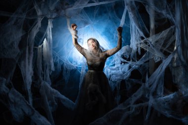 Cadılar Bayramı, dekorasyon ve korku konsepti. Örümcek ağındaki vampir kadın. Örümcek ağı takan cadı kadın. Cadılar Bayramı makyajlı ve elbiseli kız.