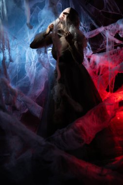 Çığlık atan, şaşkın kadın elleriyle örümcek ağını yırtıyor. Cadılar Bayramı ve korku konsepti