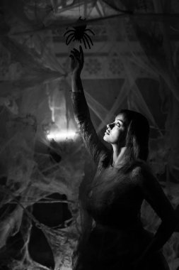 Karanlıkta örümcek ağında örümcek tutan gotik kadın. siyah beyaz fotoğraf