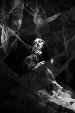 Siyah beyaz fotoğraf. Cadılar Bayramı 'nda cadı karanlık odada örümcek ağına takıldı. Gizemli