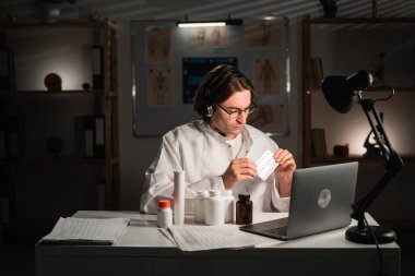 Doktor, klinikte gece vardiyasında çalışan hastalara bilgisayar kullanarak video araması yapılmasını öneriyor. Teletıp Hizmetleri. Boşluğu kopyala