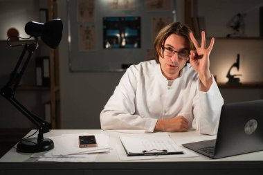 Beyaz erkek doktor, hastanede gece vardiyasında çalışan üç numaralı jesti gösteriyor. tıp ve sağlık hizmeti kavramı