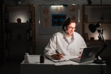 Kulaklık ve dizüstü bilgisayarı olan bir doktor, gece vardiyasında çalışan bir hastayla görüşüyor. Teletıp ya da teletıp kavramı