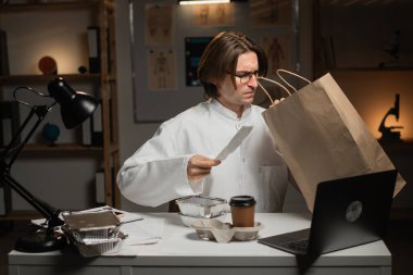 Erkek doktor, gece vardiyasında çalışırken dışarıdan yemek alıyor. Tüketim, ilaç, gıda ve insan kavramı. Boşluğu kopyala