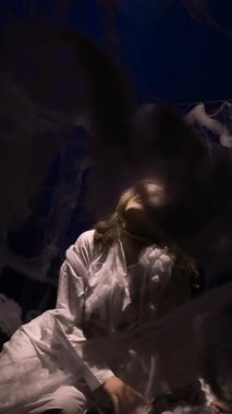 Beyaz elbiseli kadın örümcek ağının etrafında oturuyor. Tematik parti. dikey video