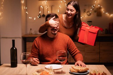 Romantik sürpriz konsepti. Sevgililer Günü 'nü evde kutlayan sevgilisine sevgililer günü hediyesi veren bir kadın. Boşluğu kopyala