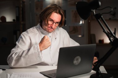 Hastanede gece vardiyası sırasında dizüstü bilgisayarla video konferansı yapan kızgın doktor. Hastayla çevrimiçi konuşma. Boşluğu kopyala