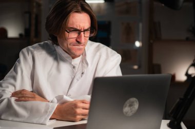 Hastanede gece vardiyası sırasında bilgisayarla video konferansı yapmaya odaklanmış bir doktor. Hastayla çevrimiçi konuşma. Boşluğu kopyala