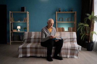 Evde yalnızlık çeken yaşlı bir adam fotoğraf albümüne bakıyor. Boşluğu kopyala