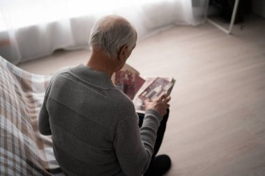 Yaşlı, üzgün bir adam eski bir fotoğrafı kayıp. Karısı evde, kanepede oturuyor. Boşluğu kopyala