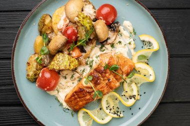 Izgara somon balığı parçaları, bol sebzeli ve mantarlı. en üstteki görünüm