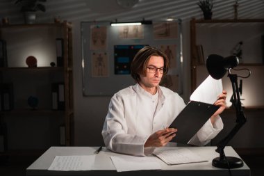 Sağlık, ilaç ve evrak işleri. Doktor sigorta yapıyor, program yapıyor ve evrakları okuyor. Hastanedeki gece vardiyası raporlarıyla GP. Boşluğu kopyala