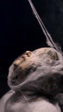 Halloween concept. Female face wrapped in spider web and tissue. copy space