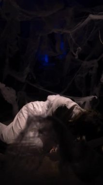 Distressed woman in restraint shirt wrapped in dense spiderweb struggling to break free, symbolizing mental pressure, addiction escape and emotional crisis in dark dramatic atmosphere.