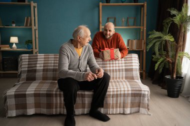 Yetişkin oğlu, yaşlı babasına evde sürpriz bir hediye veriyor. Babalar Günü ve bağlanma konsepti