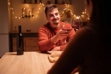 Mutlu bir adam ve bir kadın masada kadeh tokuşturarak şarap içiyorlar, evdeki sıcak akşam yemeğinde birbirlerine eşlik ediyorlar. Boşluğu kopyala