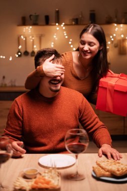 Aşık adam için sürpriz bir hediye. Erkek arkadaşının gözlerini kapayan romantik bir kadın hediye kutusunu doğum günü ya da sevgililer günü hediyesi olarak ev içindeki mutfakta veriyor. Boşluğu kopyala