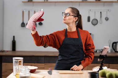 Ev hanımı portresi evdeki mutfakta cep telefonu kamerasıyla selfie çekiyor. Boşluğu kopyala