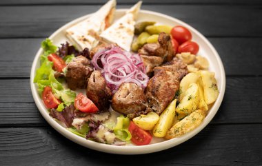 Sıcak kavrulmuş et şişleri, çıtır patatesler, dolmalık biberler, domatesler ve yanında peynirli yassı ekmekle süslenmiş lezzetli yemekler..
