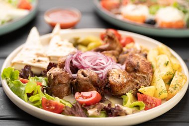 Lezzetli ızgara domuz eti ya da sığır kebabı şiş, kızarmış patates dilimleri, taze kızarmış sebzeler ve restoran tabağında Gürcistan suluguni peyniri ile servis edilir..