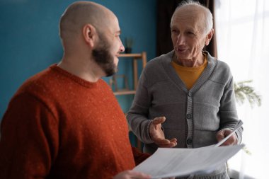 Muhasebe, finans veya geri ödeme, ipotek ve vergi. Evde yetişkin bir oğlu olan büyük baba banka ödemeleri için belgeleri okuyor. Boşluğu kopyala