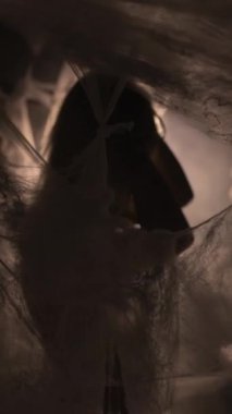 Young woman with makeup and loose hair dancing gracefully in the dark. Concept of mystery, dramatic movement, dark aesthetic, and expressive choreography. vertical video