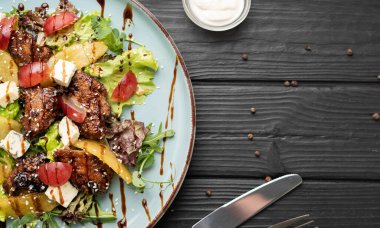 Tavada kızarmış tavuk ciğeri, karamelize armut ve koyu ahşap arka planda servis edilen keskin Dorr Blue peyniri içeren gurme salatası. Konsept restoran menüsü, güzel yemekler ve aperatif yemekler. düz yat