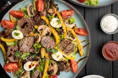 Biftekli sıcak salata, ızgara sebze, bıldırcın yumurtası ve bir restoran ortamında güzel bir şekilde servis edilmiş balzamik sos. Güzel yemekler, gurme yemekleri, özel menü öğelerini ve sağlıklı beslenmeyi hesaba katın. Üst görünüm