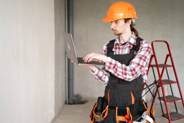 Genç inşaatçının portresi, ustabaşı ya da turuncu miğferli ev bilgisayarı olan tamirci.