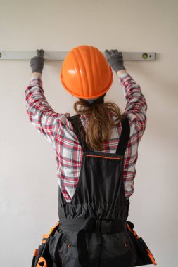 Müteahhit, tamirci, üniformalı müteahhit balon ruhu seviyesini kullanarak duvarı ölçüyor. konut yenileme ve inşaat konsepti.