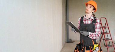 Meslek, inşaat ve inşaat kavramı. İnşaat alanında çalışan genç bir işçi ya da inşaatçı. Pankart. Boşluğu kopyala