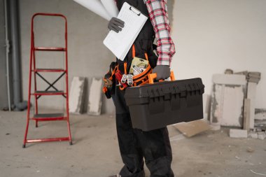 Alet çantası ve kağıt ev planı olan profesyonel bir tamirci, yakın plan. Boşluğu kopyala