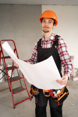 Üniformalı mimar ya da müteahhit ev yenileme planı tutuyor, tadilat projesi geliştirmeyi planlıyor. Boşluğu kopyala