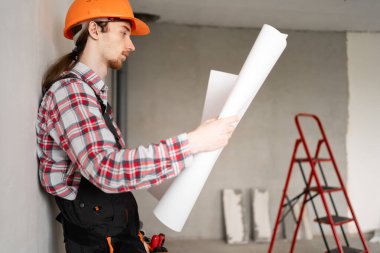 Üniformalı mimar ya da müteahhit ev yenileme planı tutuyor, tadilat projesi geliştirmeyi planlıyor. Boşluğu kopyala