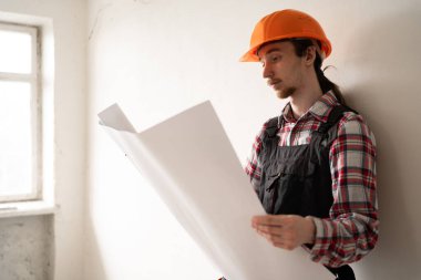 Ciddi bir müteahhit ev yenilemesi planlıyor. Kağıt planları ve başarılı bir yenileme planı. Boşluğu kopyala