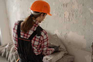 İnşaat enkazı toplayan kasklı genç bir inşaatçı. Ev tadilatı ve onarım. Boşluğu kopyala